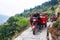 Farmers on motorbikes with trailers, riding along narrow road