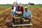 Farmers posing on vegetable plantation near pile of plastic boxes with freshly picked potatoes. Concept of successful