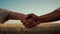 Farmers shake hands at golden harvest field closeup. Agribusiness partners deal.