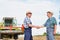 Farmers shaking hands against harvester in field