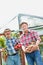 Farmers talking while carrying newly harvest carrots, tomatoes and potatoes at farm