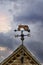 Farmers weathervane metal red old tractor on barn rooftop showing north east south west wind direction with arrow pointer in front