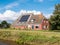 Farmhouse with solar panels on roof by Dokkumer Ee canal in Friesland, Netherlands