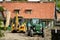 In the farmhouse yard stands excavator and a tractor with a trai