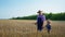 Farming, grandfather tells male grandchild in straw hats about agriculture while holding ripe ears of wheat