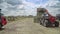 Farming tractor loading haystacks on agricultural field