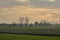 Farmland with bare trees under a  cloudy evenig sky with dark clouds and yellow glow  in the Flemish countryside