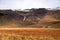 Farmland dotted with Wrapped Hay Bales at the Botton of Majestic Mountains