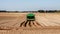 Farmland with a green tractor plowing the land for planting potatoes, preparing the land in a farm field