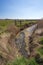 Farmland irrigation trench. Grazing land with fence bordered by