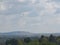 Farmland landscapes with many large multicolored green leafy treetops with a grey cloudy sky