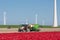 Farmland with tractor planting potatoes between tulip fields and windturbines