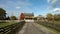 Farmland with a wooden fence under a cloudy sky with the sun shinning through