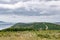 Farmlands and trees by the sea panorama, distant view of land by the ocean in United Kingdom, cloudy sea and green