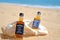 Faro, Portugal - 12/10/2018: Two little bottles Jack Daniels whiskey in the big ocean shell stand on the sand. Alcoholic party in