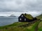 Faroe Islands. House with grass roof on the slope of hill. Hazy landscape.