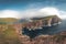 Faroe Islands Traelanipa the slaves rock cliff is seen rising over the ocean next to lake Sorvagsvatn. Clouds and blue