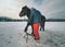 Farrier assistant keeps brown horse with front leg on steel tripod