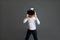 Fascinated girl in white long sleeve shirt wearing virtual reality glasses over grey background