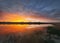 Fascinating sunset reflecting on the lake surface. Idyllic landscape, vertical background. Silent and tranquil evening scene with