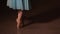 Fashion ballerina dancing in a dark ballet class. The girl performs dance steps in a stage costume. Slow motion.