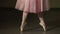 Fashion ballerina dancing in a dark ballet class. The girl performs dance steps in a stage costume. Slow motion.