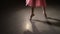 Fashion ballerina dancing in a dark ballet class. The girl performs dance steps in a stage costume. Slow motion.