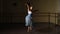 Fashion ballerina dancing in a dark ballet class. The girl performs dance steps in a stage costume. Slow motion.