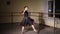 Fashion ballerina dancing in a dark ballet class. The girl performs dance steps in a stage costume. Slow motion.