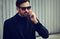 Fashion beard style business handsome male model in fashion sunglasses and blue coat with serious concentrated look talking on