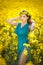 Fashion beautiful young woman in blue dress smiling in rapeseed field in bright sunny day