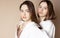 Fashion beauty models two sisters twins beautiful nude girls looking at the camera isolated on beige background