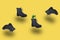 Fashion black boots with grass in air on yellow background. Modern stylish creative minimalism, levitation trendy shoes, plant