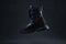 Fashion black unbranded boot flying on dark background. Black winter walking shoes levitate in air