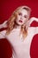 fashion blonde with bright red makeup on bright red background. Girl in lingerie body with perfect figure Professional makeup