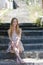 Fashion blonde wearing flower dress sitting on stone stairs