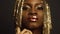 Fashion close-up portrait of surreal mysterious black african american female model with golden faceart and big glossy