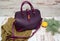 Fashion concept. Purple lady`s bag, warm sweater on a wooden background, spruce branch and orange