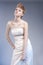 Fashion Concepts. Tall Young and Blond Woman in Tailored Wedding Dress Posing Against Gray