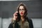 Fashion consept: beatiful young girl with long hair, glasses, red lips standing near modern wall wearing in green suit and grey je