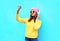 Fashion cool girl in headphones listening music taking photo makes self portrait on smartphone wearing a colorful clothes