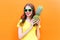 Fashion cool smiling girl in sunglasses with pineapple over colorful orange