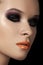 Fashion dark smoky eyes makeup, black eyeshadows, orange lips.