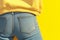 Fashion detail Back pockets of blue jeans on yellow background