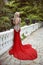 Fashion elegant blond woman model in red gown with long train of