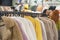 Fashion faux fur coats hanging on rack in clothing store, various colors, blurred interior, girls, customers