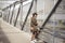 Fashion female model dressed casual in a grungy location. Fashion blogger in military shirt and hat on a pedestrian bridge