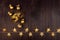 Fashion festive theatre background - golden glitter lace venetian mask, decorative balls and glowing stars on dark brown wood.