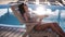 Fashion footage of beautiful tanned woman with brown hair in elegant silver bikini relaxing beside a swimming pool in