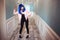 Fashion freak. Glamour synthetic girl, fake doll with empty look and blue hair is moving in long corridor. Stylish woman
